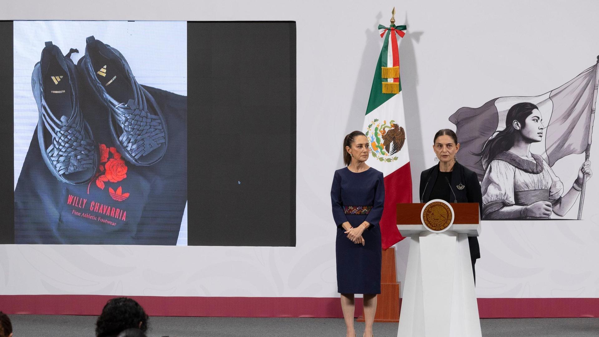 Mexikos Präsidentin Claudia Sheinbaum (l) und die Vizeministerin für kulturelle Entwicklung Mariana Núñez zeigen auf einer Pressekonferenz ein Bild von den Sandalen Oaxaca Slip-On von adidas. Mexikos Präsidentin Claudia Sheinbaum (l) und die Vizeministerin für kulturelle Entwicklung Mariana Núñez zeigen auf einer Pressekonferenz ein Bild von den Sandalen Oaxaca Slip-On von adidas.