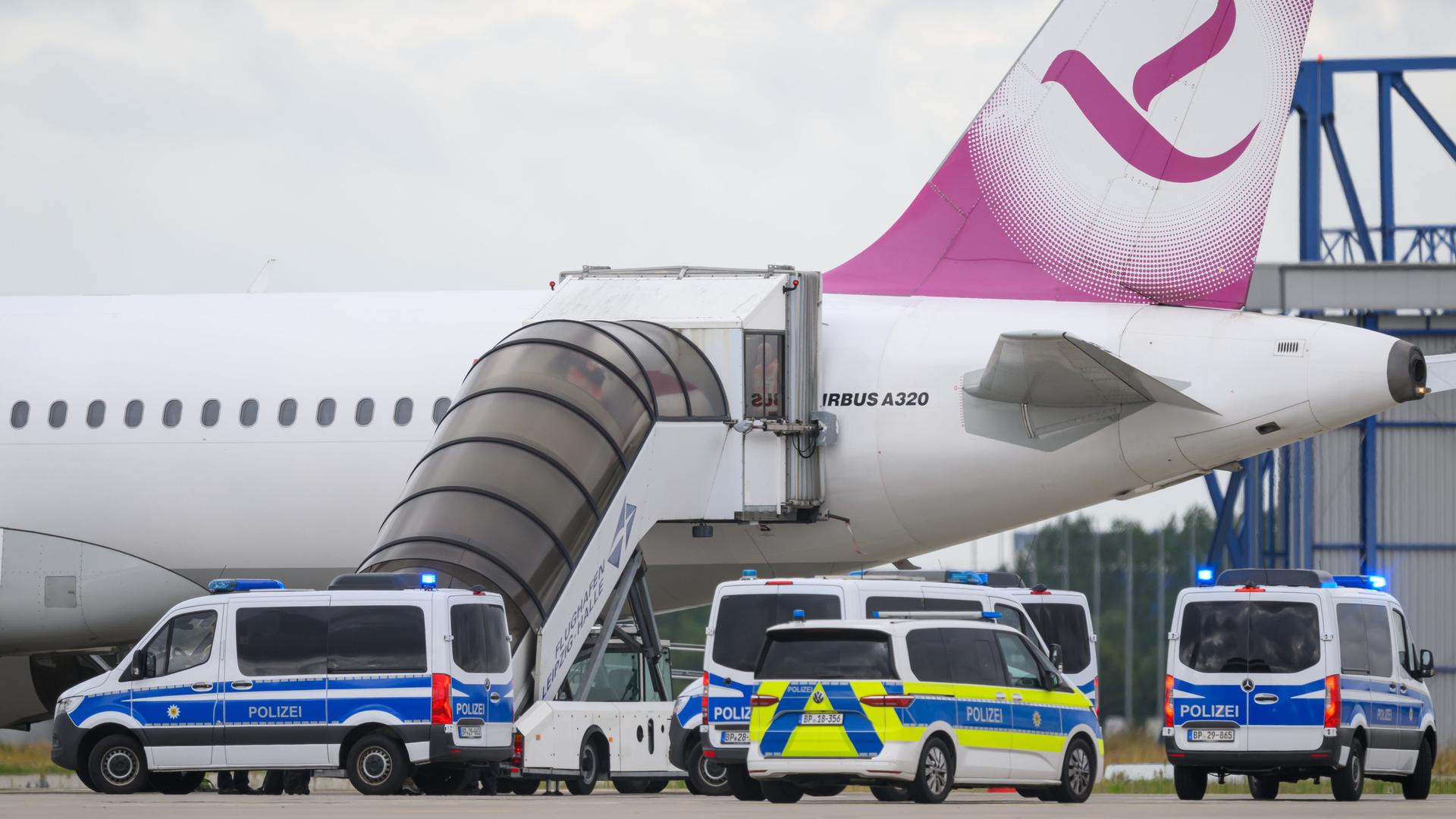 Polizeifahrzeug fahren auf dem Flughafen Leipzig/Halle an einem Airbus vor. 