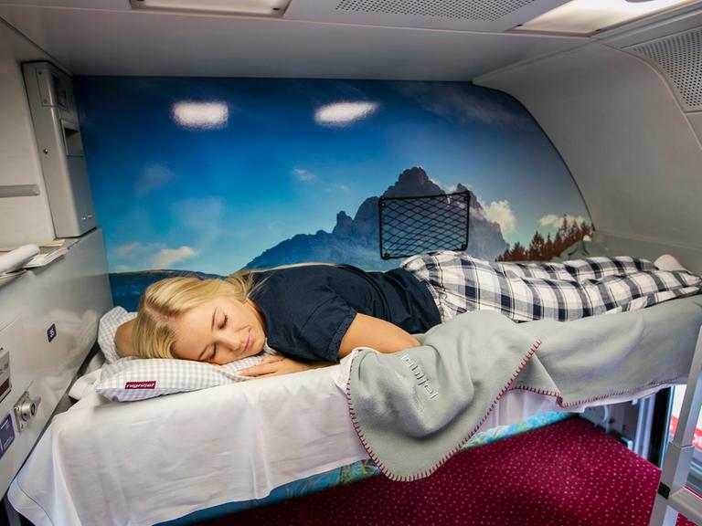 Eine junge Frau schläft in einem Nachtzug.