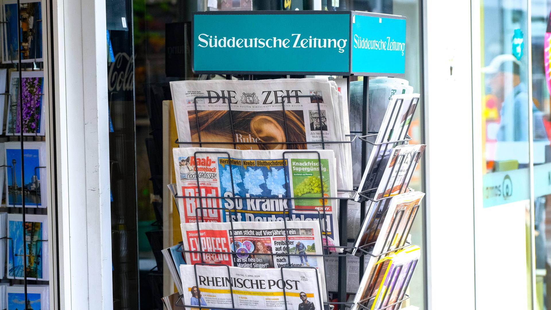 Verschiedene deutsche Zeitungen hängen in einem Zeitungsständer.
