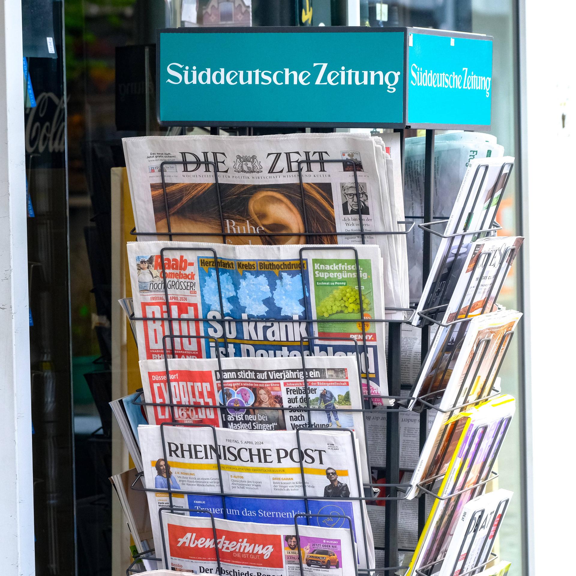 Verschiedene deutsche Zeitungen hängen in einem Zeitungsständer.