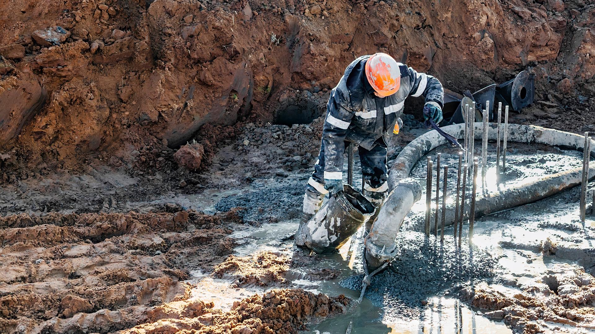 Ein Arbeiter reinigt ein Pfahlfundament auf einer Baustelle. Ein Arbeiter reinigt ein Pfahlfundament auf einer Baustelle.