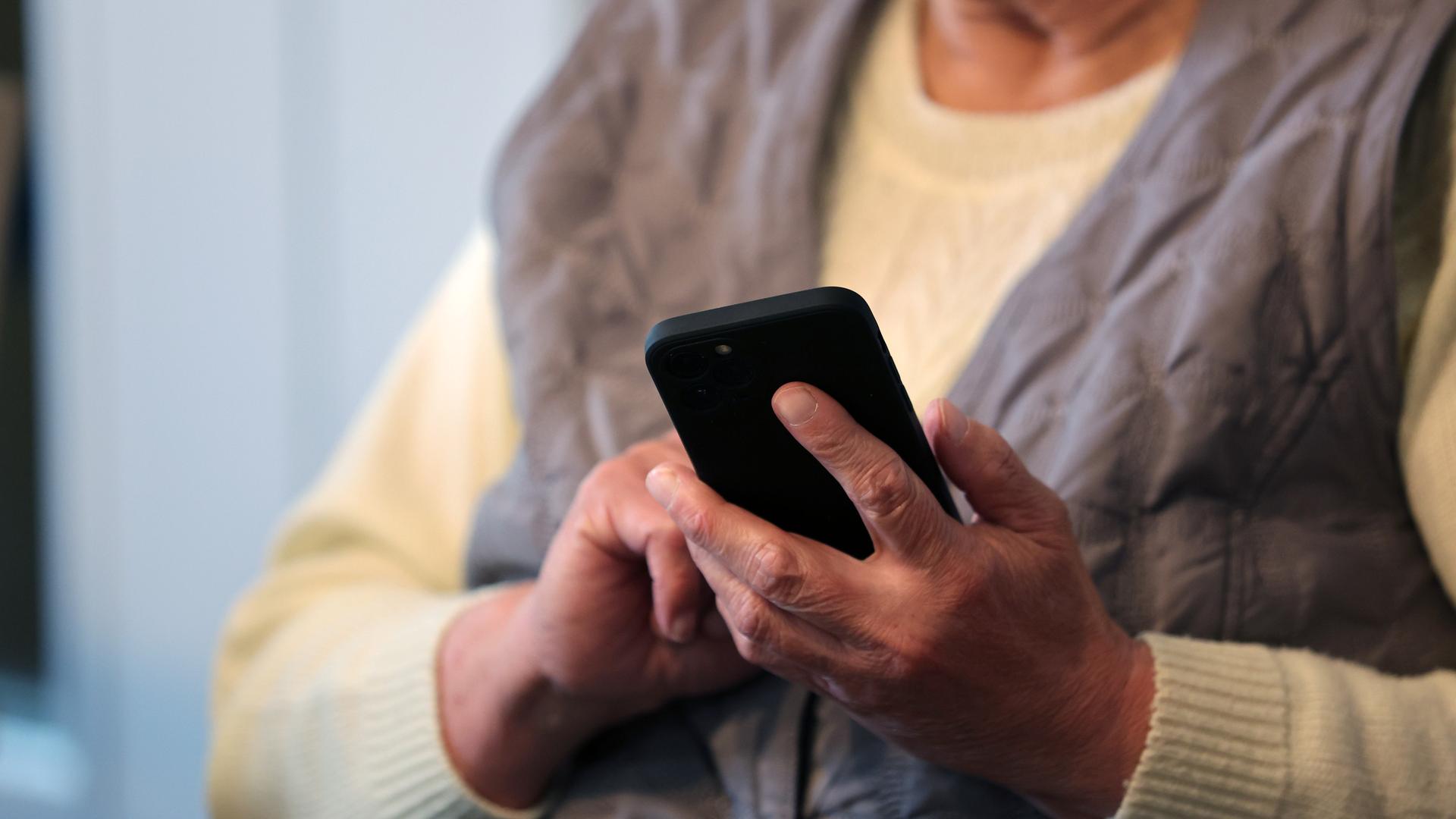 Eine Seniorin schreibt eine Nachricht in ihr Handy. 