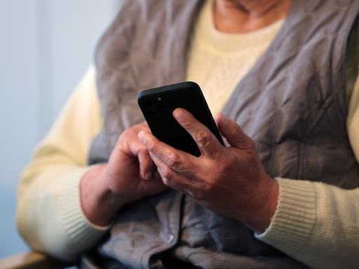 Eine Seniorin schreibt eine Nachricht in ihr Handy. 