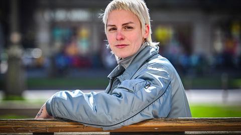Helene Bukowski sitzt auf einer Bank und schaut direkt und freundlich in die Kamera. Im Hintergrund ist eine Straße zu erkennen.