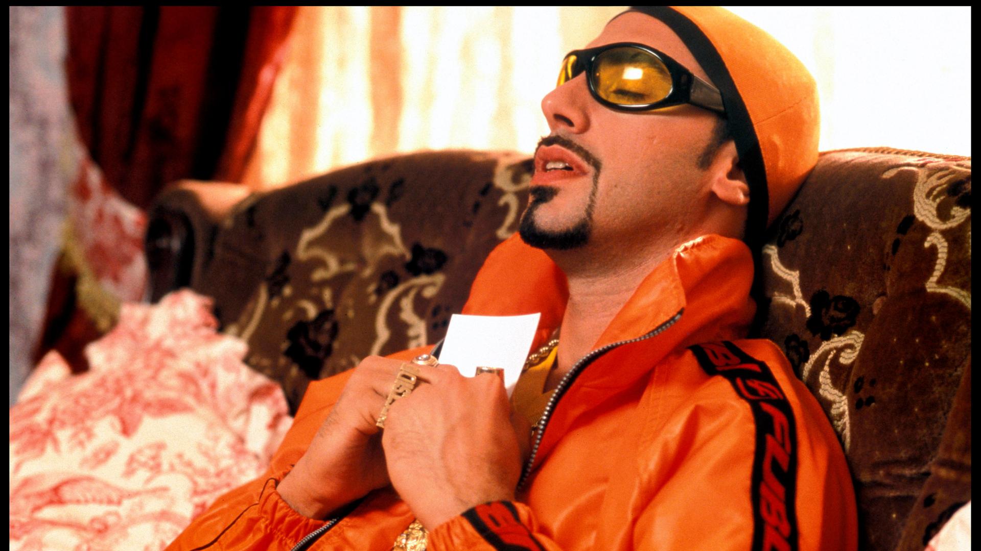 Sacha Baron Cohen als Rapper, auffällige Brille, Bling-Bling, Goldkette, Porträt, an sein Herz gedrückt; alternativer Titel. Sacha Baron Cohen als Rapper, auffällige Brille, Bling-Bling, Goldkette, Porträt, an sein Herz gedrückt; alternativer Titel.
