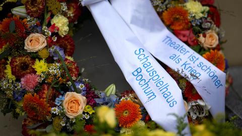 Ein Kranz mit Blumen und dem Schriftzug "Theater ist schoener schöner als Krieg"