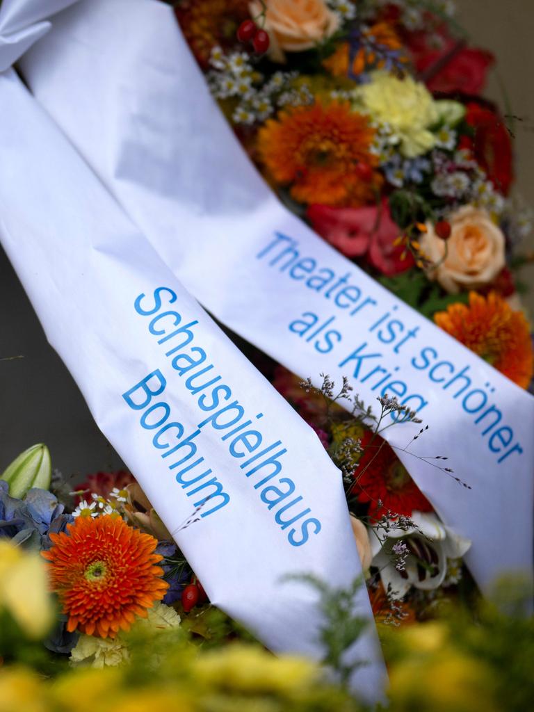 Ein Kranz mit Blumen und dem Schriftzug "Theater ist schoener schöner als Krieg"