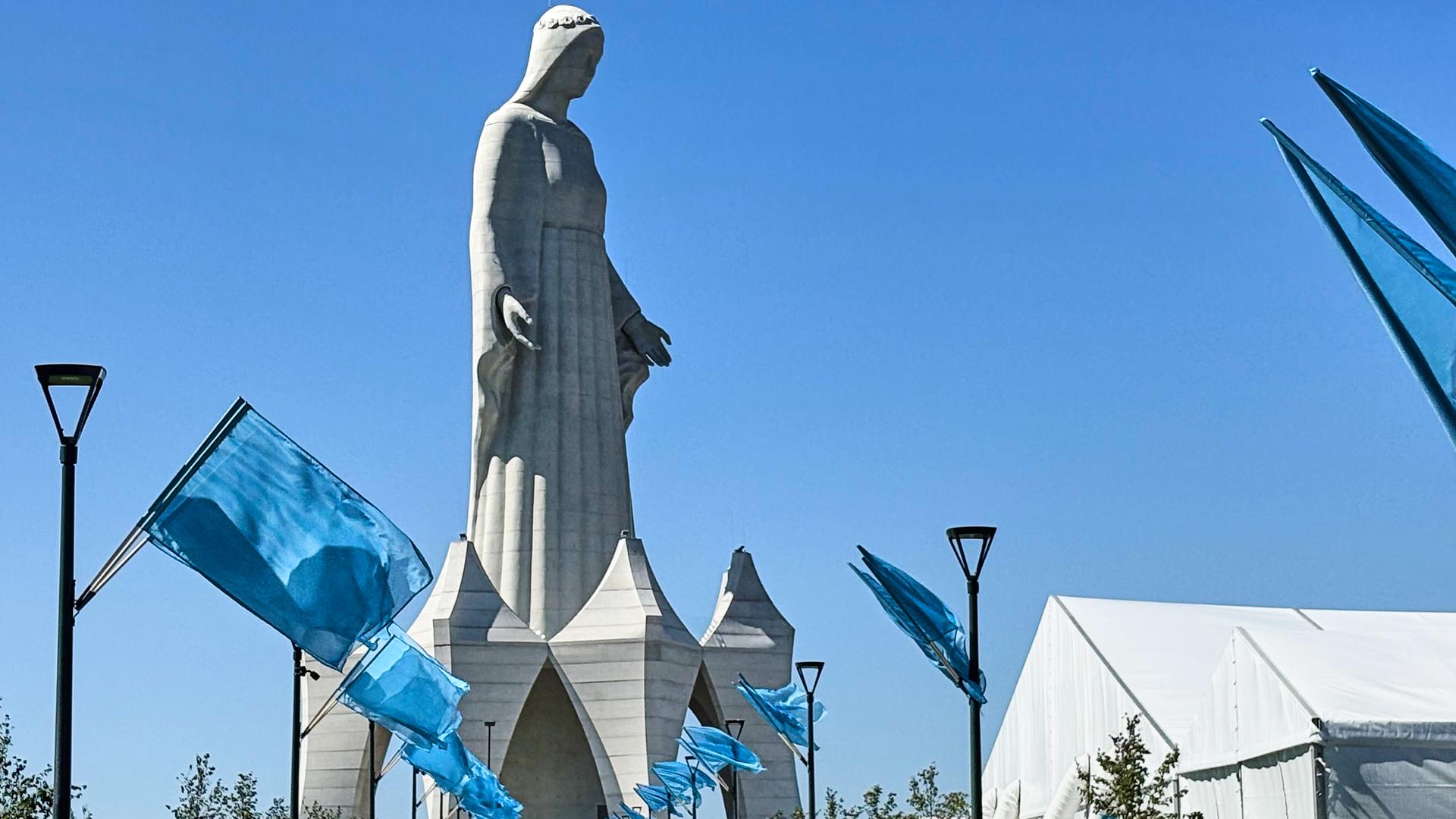 Fahnen wehen vor einer riesigen Marien-Statue Fahnen wehen vor einer riesigen Marien-Statue