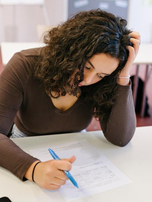 Eine Schülerin ist offensichtlich angestrengt von den Aufgaben, die vor ihr liegen.