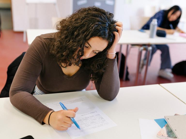 Eine Schülerin ist offensichtlich angestrengt von den Aufgaben, die vor ihr liegen.