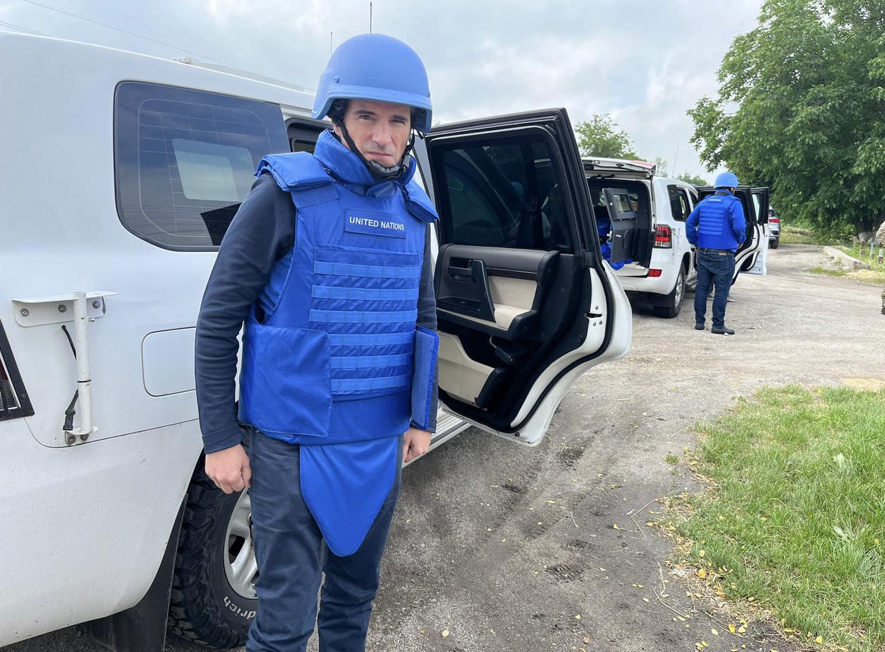 Grossi steigt aus einem Auto. Er trägt einen blauen Helm und eine blaue Strahlenschutzweste.