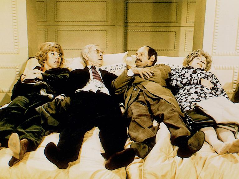 Szene aus dem Sketch "Der Bettenkauf" mit Vicco von Bülow alias Loriot, Evelyn Hamann, Ingeborg Heydorn und Heinz Meier. Zwei Ehepaar liegen in einem Bettengeschäft nebeneinander in einem Bett.