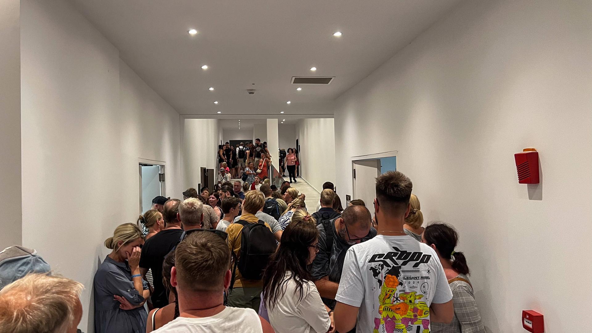 Touristen warten in einem Hotel auf Rhodos auf ihre Abreise. Zahlreiche Menschen stehen dicht gedrängt in einem Gang. Touristen warten in einem Hotel auf Rhodos auf ihre Abreise. Zahlreiche Menschen stehen dicht gedrängt in einem Gang.