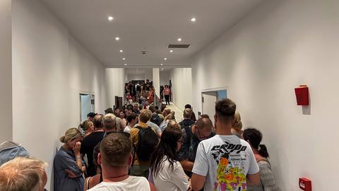 Touristen warten in einem Hotel auf Rhodos auf ihre Abreise. Zahlreiche Menschen stehen dicht gedrängt in einem Gang.