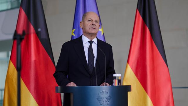 Bundeskanzler Olaf Scholz steht an einem Rednerpult und gibt ein Statement zum Ausgang der US-Wahl ab. Im Hintergrund sind zwei Deutschland-Flaggen und eine Europa-Flagge zu sehen. 