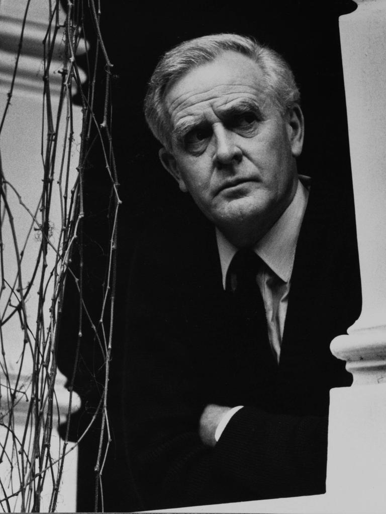 John le Carré im Jahr 2000 auf einem Schwarz-Weiß-Portrait in seinem Zuhause in Hampstead. Er schaut zwischen zwei Säulen hindurch. Er trägt einen dunklen Anzug und Krawatte und ein helles Hemd.