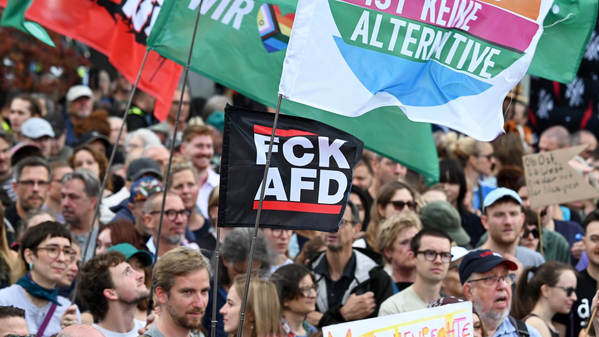 Auf dem Bild sind viele Menschen bei einer Demonstration zu sehen. Die Menschen stehen dicht beieinander. Sie tragen Fahnen und Schilder. Auf dem Bild sind viele Menschen bei einer Demonstration zu sehen. Die Menschen stehen dicht beieinander. Sie tragen Fahnen und Schilder.