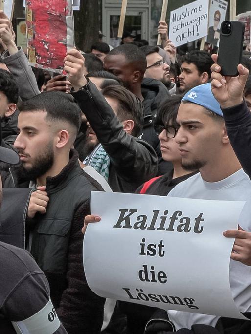 Junge muslimische Männer bei einer Islamisten-Demo in Hamburg. Auf einem Schild steht "Kalifat ist die Lösung".
