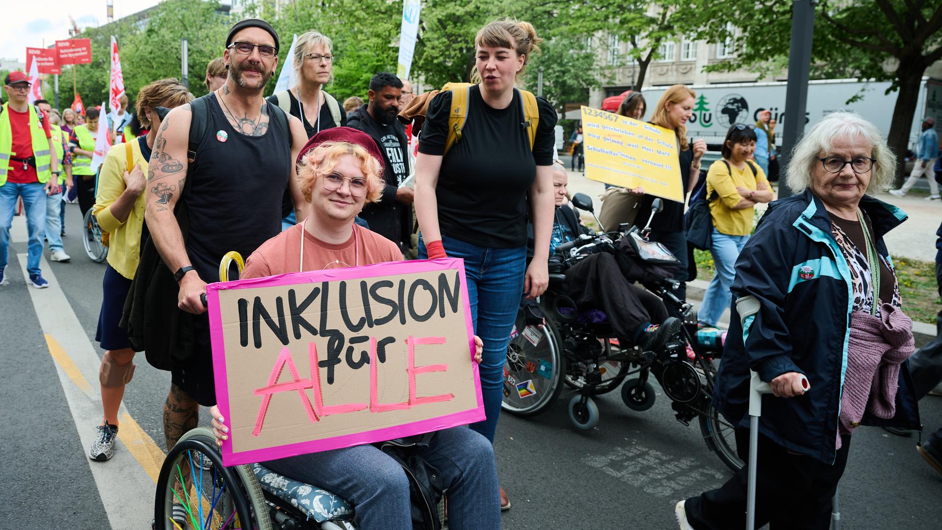 "Inklusion für Alle" steht auf einem Plakat, das eine Person im Rollstuhl bei einer Demonstration hält.  