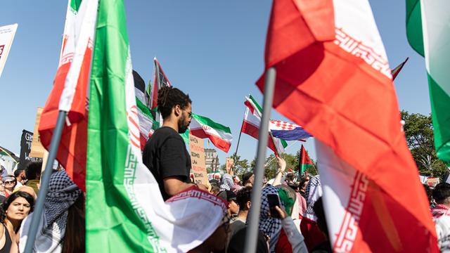Die Demonstration in Berlin gegen den Krieg im Gazastreifen. Man sieht viele palästinensische Fahnen, Demonstranten und in der Mitte einen Mann. Der Mann steht höher als die anderen Demonstranten.