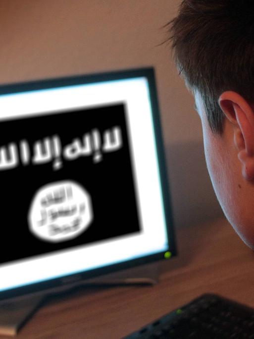 Ein Jugendlicher schaut auf einen Computerbildschirm, auf dem die Flagge des Islamischen Staates abgebildet ist.