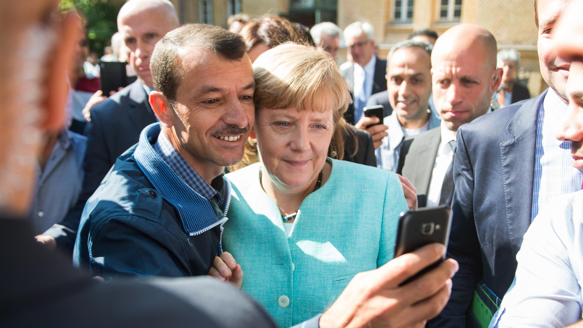 Bundeskanzlerin Angela Merkel (CDU) lässt sich nach dem Besuch einer Erstaufnahmeeinrichtung für Asylbewerber der Arbeiterwohlfahrt (AWO) in Berlin-Spandau für ein Selfie zusammen mit einem Flüchtling fotografieren. Bundeskanzlerin Angela Merkel (CDU) lässt sich nach dem Besuch einer Erstaufnahmeeinrichtung für Asylbewerber der Arbeiterwohlfahrt (AWO) in Berlin-Spandau für ein Selfie zusammen mit einem Flüchtling fotografieren.