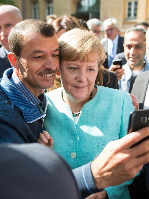 Bundeskanzlerin Angela Merkel (CDU) lässt sich nach dem Besuch einer Erstaufnahmeeinrichtung für Asylbewerber der Arbeiterwohlfahrt (AWO) in Berlin-Spandau für ein Selfie zusammen mit einem Flüchtling fotografieren.