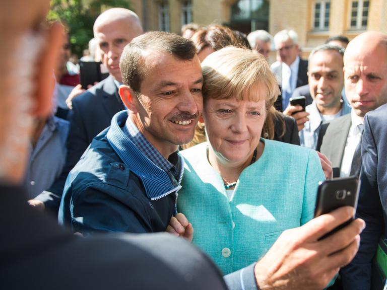 Bundeskanzlerin Angela Merkel (CDU) lässt sich nach dem Besuch einer Erstaufnahmeeinrichtung für Asylbewerber der Arbeiterwohlfahrt (AWO) in Berlin-Spandau für ein Selfie zusammen mit einem Flüchtling fotografieren.