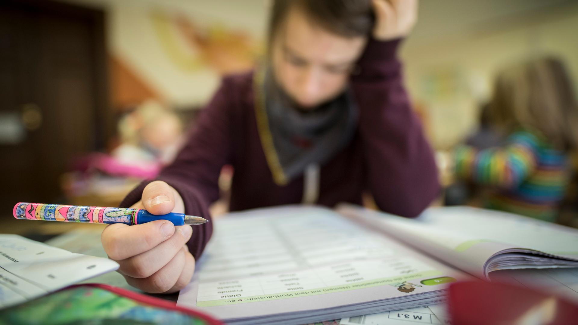 Ein Schüler liest konzentriert während des Unterrichts. In der Hand hält er einen Füllfederhalter.