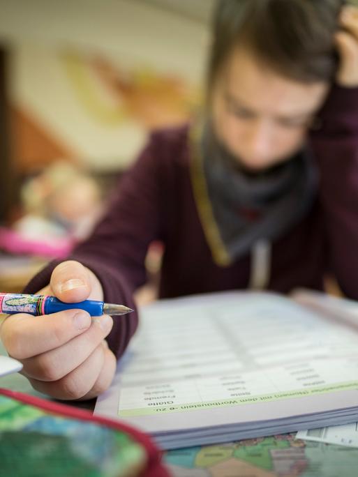 Ein Schüler liest konzentriert während des Unterrichts. In der Hand hält er einen Füllfederhalter.