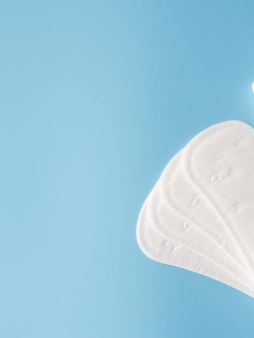 Sanitary pad and tampons on blue background. Concept of feminine hygiene during menstruation. Copyright: xAllaRudenkox P