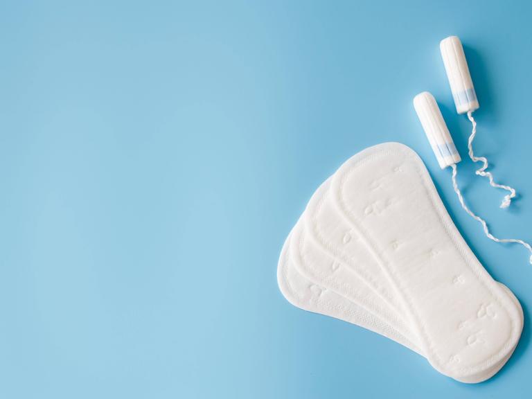 Sanitary pad and tampons on blue background. Concept of feminine hygiene during menstruation. Copyright: xAllaRudenkox P