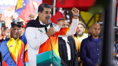 Venezualeas Präsident Maduro steht auf einer Bühne, spricht in ein Mikrofon und reckt die linke Faust in die Höhe. Hinter ihm stehen weitere Personen auf der Bühne.