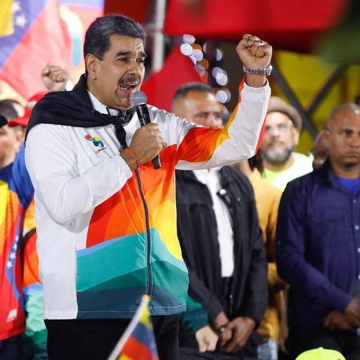 Venezualeas Präsident Maduro steht auf einer Bühne, spricht in ein Mikrofon und reckt die linke Faust in die Höhe. Hinter ihm stehen weitere Personen auf der Bühne.