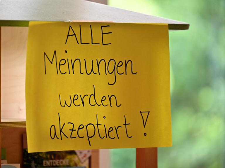 Auf einem befestigten, hängenden Blatt Papier steht: "Alle Meinungen werden akzeptiert".