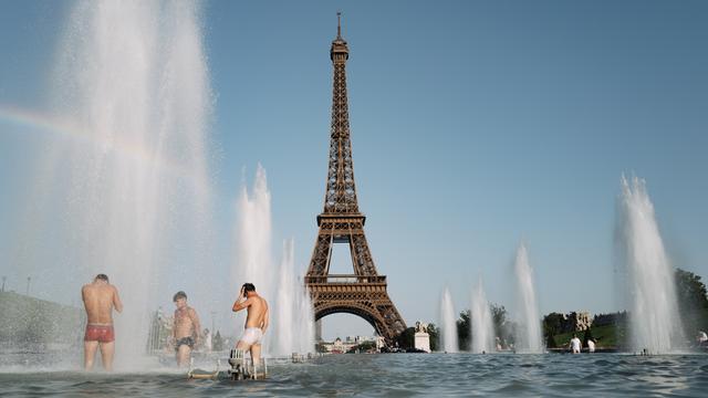 Mehrere Menschen kühlen sich in einem Spring-Brunnen-Becken vor dem Eiffelturm ab.