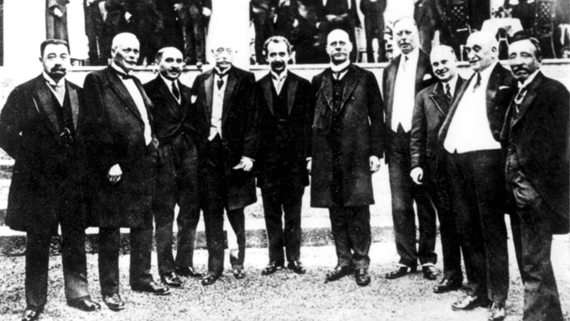 Schwarz-Weiß-Foto zeigt zehn Männer in dunklen Anzügen  einen Halbkreis bildend 
