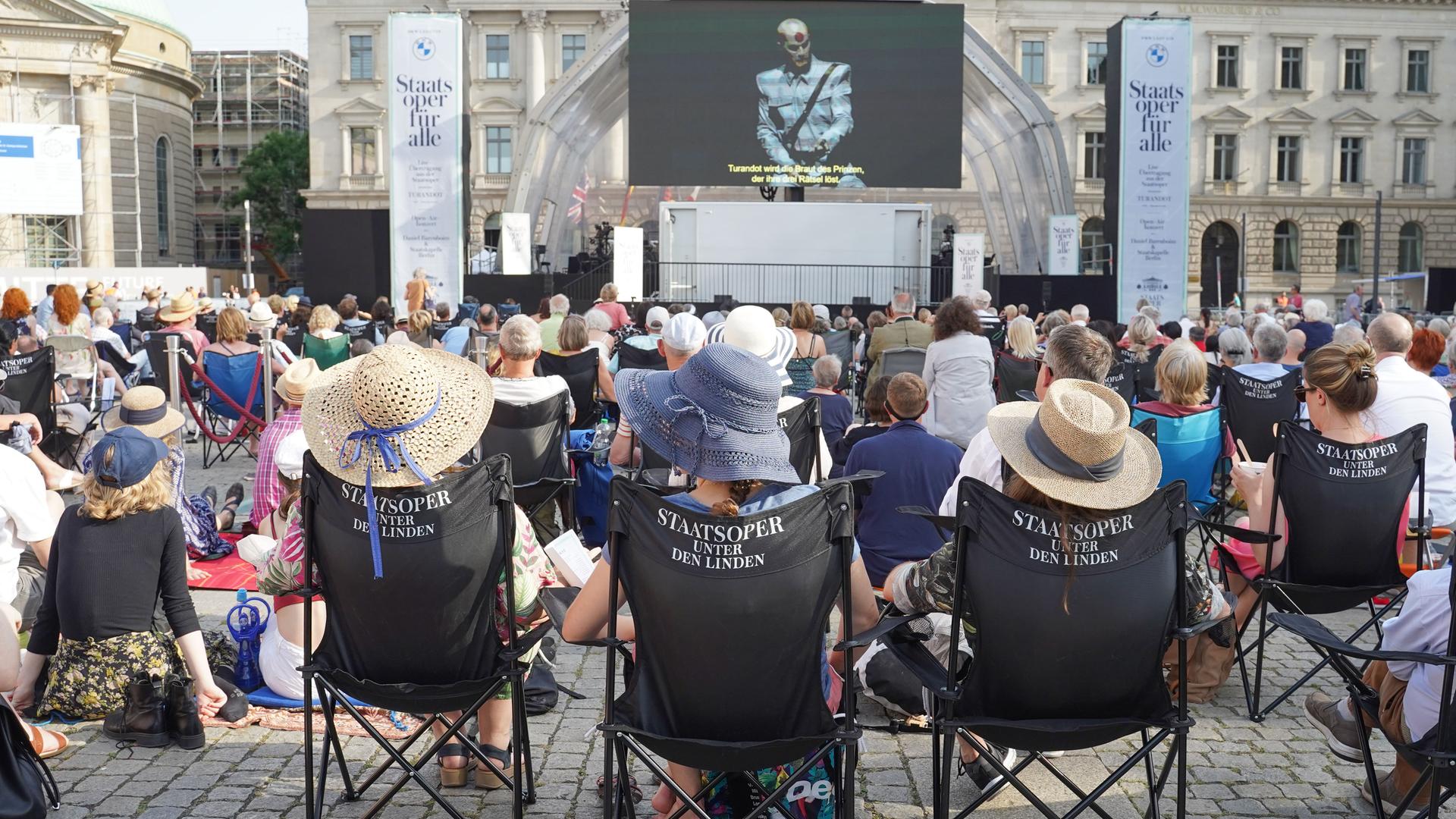 Zahlreiche Menschen sitzen vor einer Leinwand. Dort wird "Turandot" übertragen. Zahlreiche Menschen sitzen vor einer Leinwand. Dort wird "Turandot" übertragen.