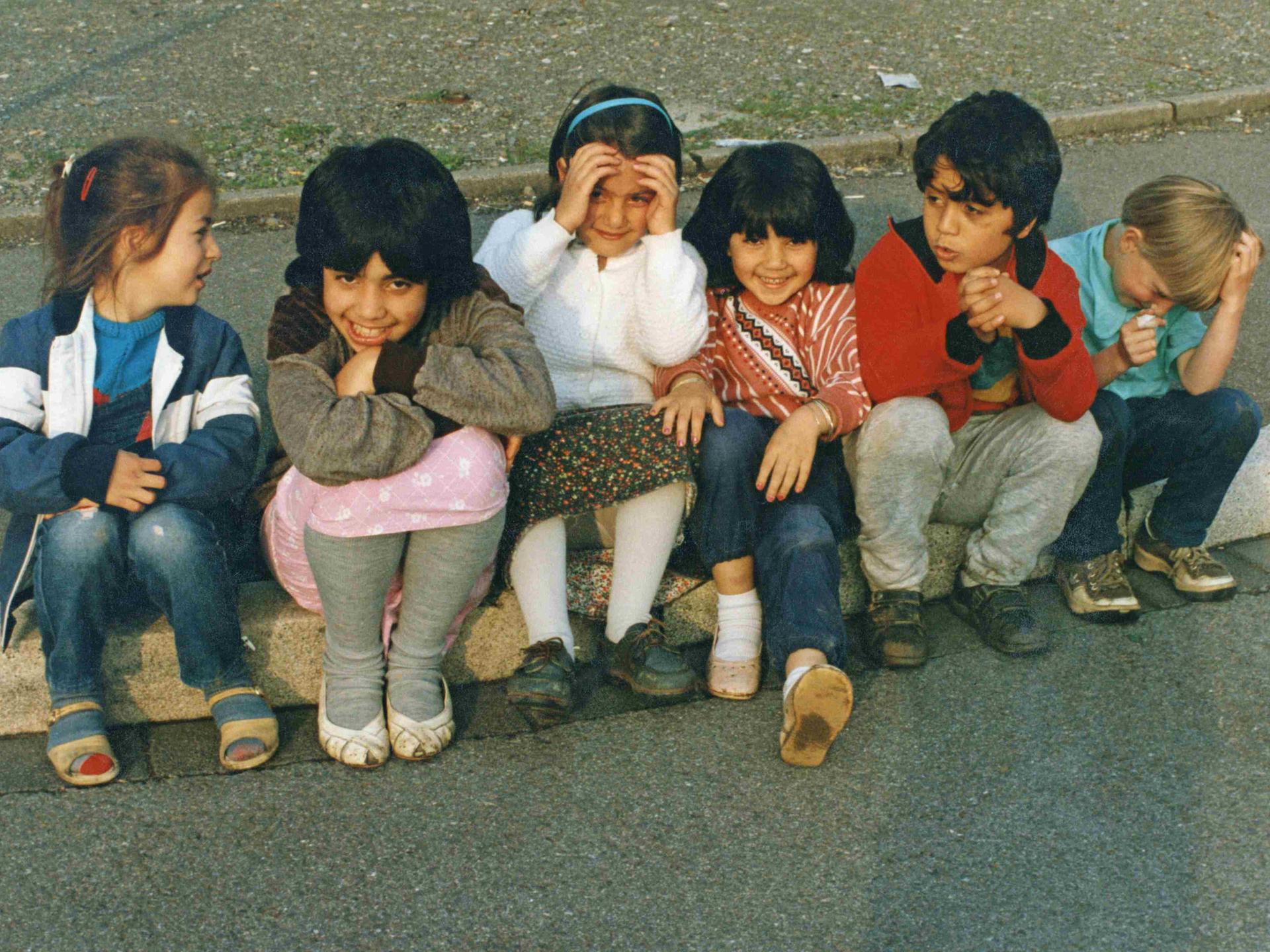 1990: Kinder mit türkischen Wurzeln sitzen auf einem Bordstein.