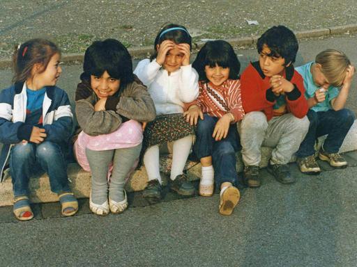 1990: Kinder mit türkischen Wurzeln sitzen auf einem Bordstein.