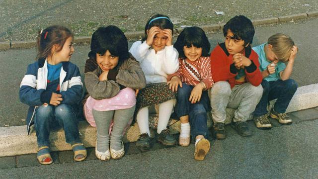 1990: Kinder mit türkischen Wurzeln sitzen auf einem Bordstein.