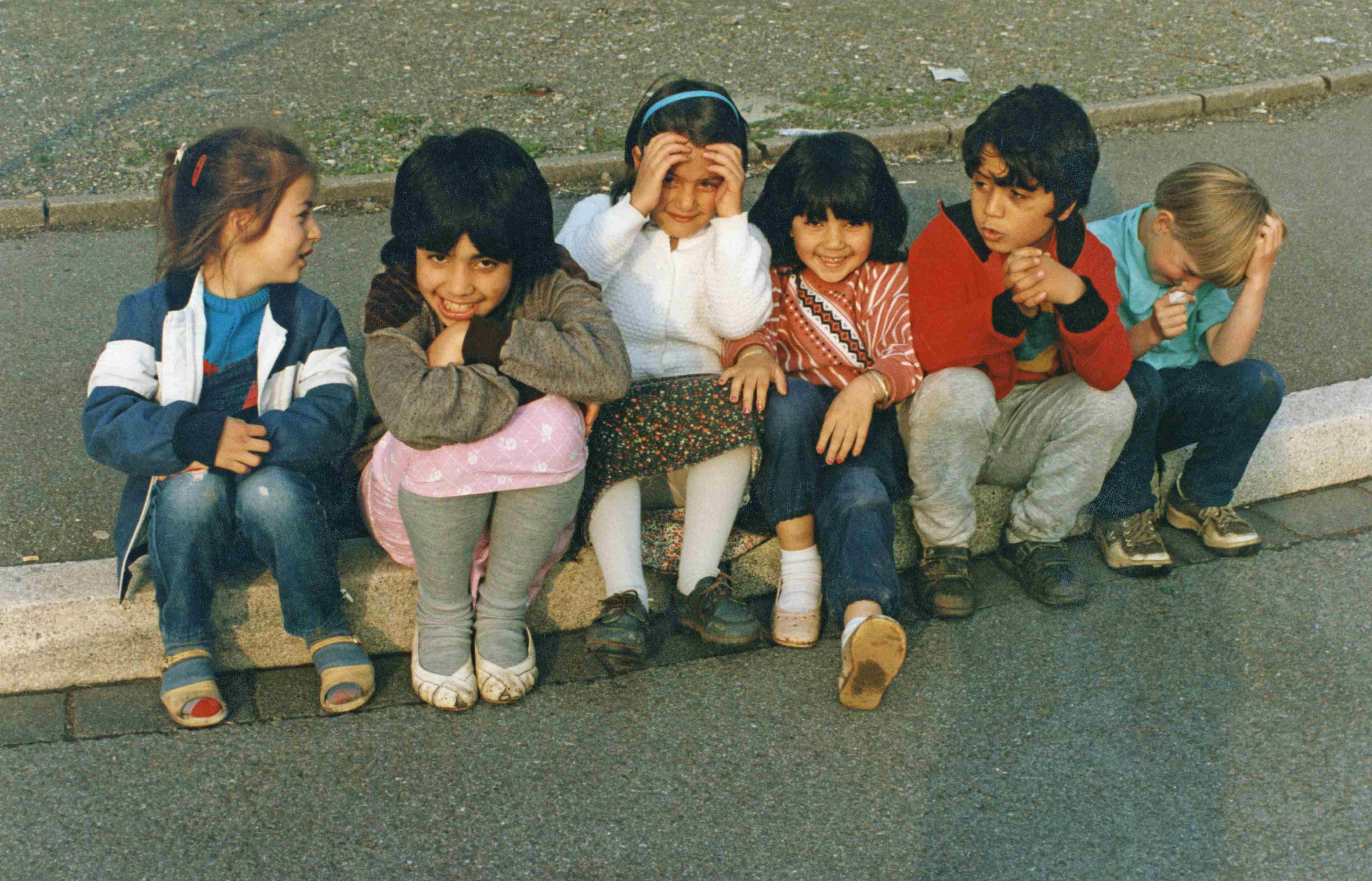 1990: Kinder mit türkischen Wurzeln sitzen auf einem Bordstein.
