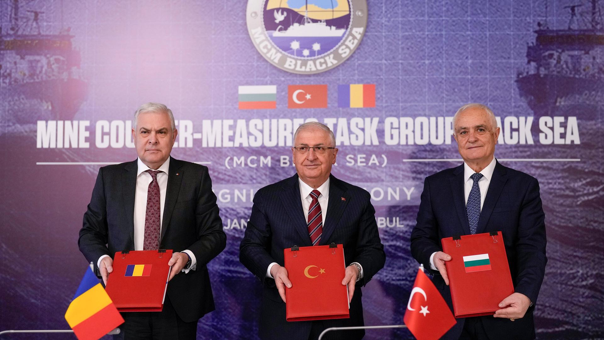 Der türkische Verteidigungsminister Guler, sein rumänischer Kollege Tilvar und der bulgarische stellvertretende Verteidigungsminister Zypryanov stehen nach der Unterzeichnung des Papiers nebeneinander und halten es in die Kamera.