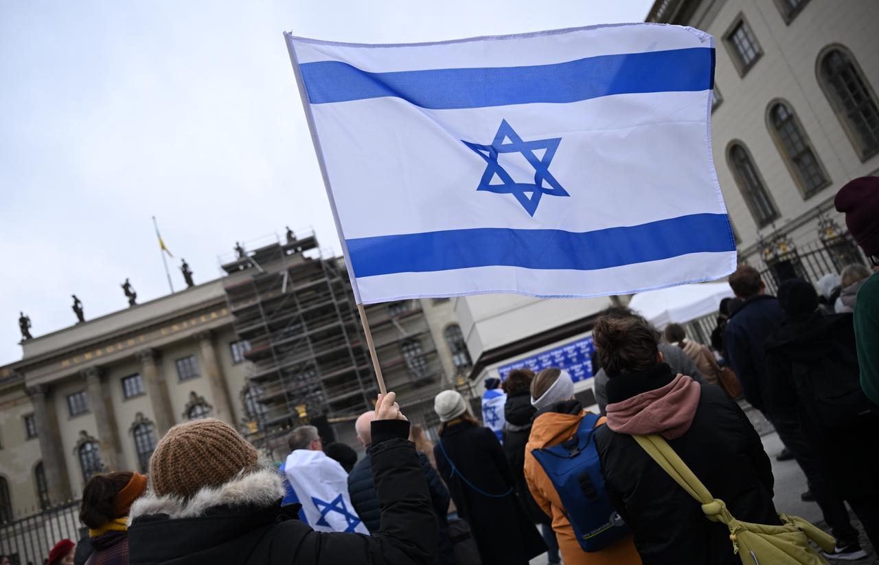 Mehrere Menschen stehen vor einem Universitätsgebäude. Eine Israel-Flagge wird in die Höhe gehalten.