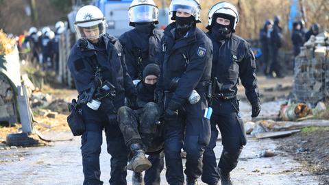Polizisten tragen einen Klimaaktivisten vom besetzten Braunkohleort Lützerath weg.
