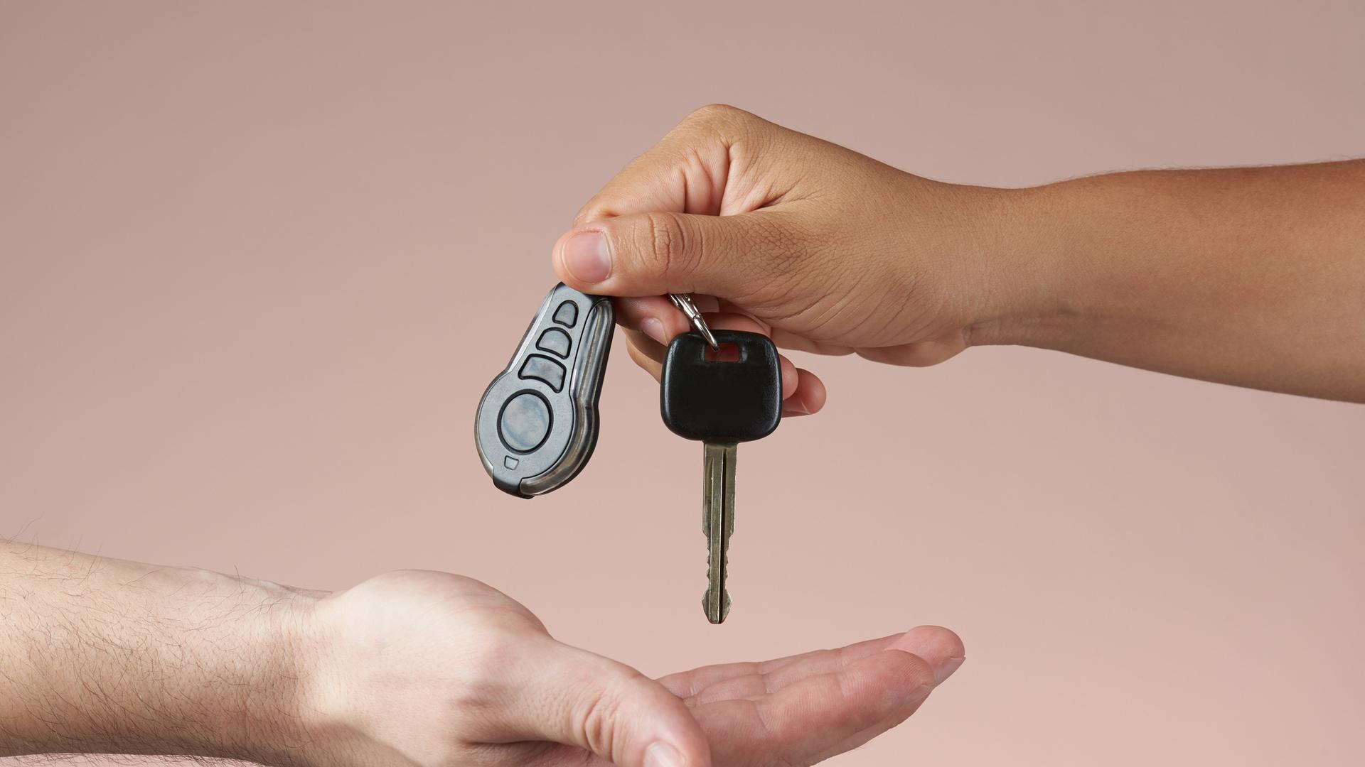 Ein Autoschlüssel wird von einer Hand in die andere gegeben.