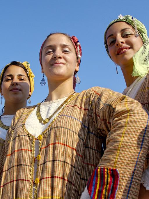 Vier junge Frauen in traditionellen, zyprischen Kleidern stehen in Limassol beieinander und lächeln in die Kamera.