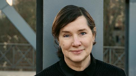 Porträtfoto von Annette Schuhmann vor einem Stahlträger. Porträtfoto von Annette Schuhmann vor einem Stahlträger.