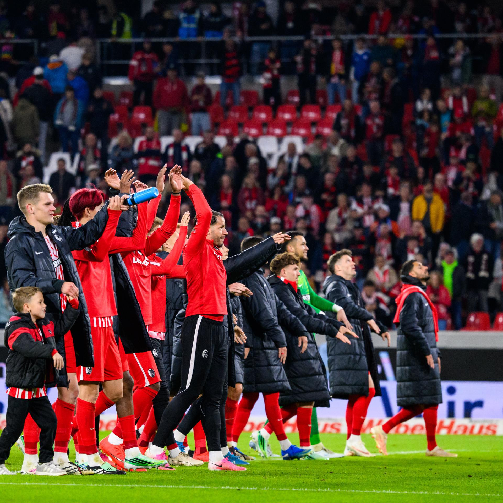 Die Spieler des SC Freiburg jubeln nach dem Spiel über den Sieg und bedanken sich mit einer Laola-Welle bei den Fans für die Unterstützung.